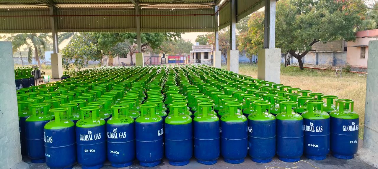 Rows of green-top, navy Global Gas 21 kg cylinders in a covered shed
